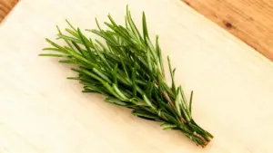 Rametto fresco di rosmarino su un tagliere di legno chiaro