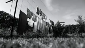 Bucato steso all'aperto su fili tra due pali in un giardino con cielo nuvoloso