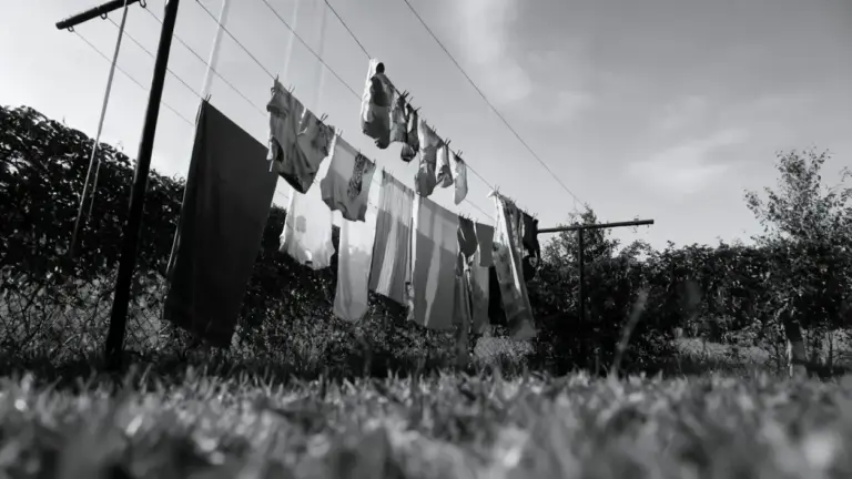 Bucato steso all'aperto su fili tra due pali in un giardino con cielo nuvoloso