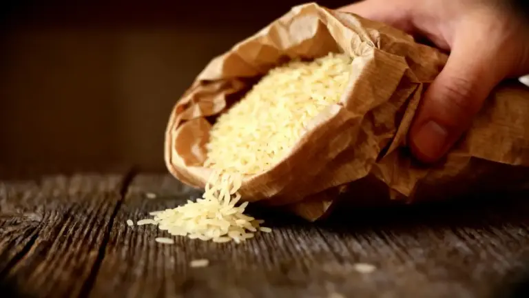 Riso basmati crudo versato da un sacchetto di carta su un tavolo in legno