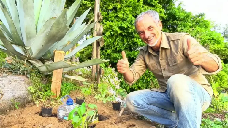 Persona sorridente accanto a un orto con bottiglie usate per irrigazione